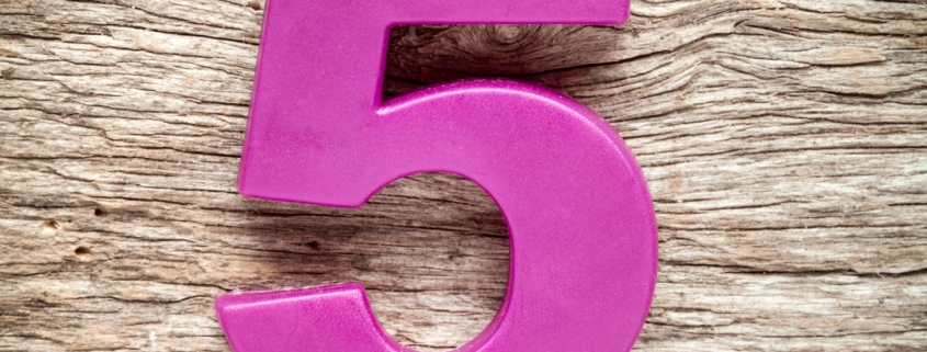 Purple number five on the wooden background