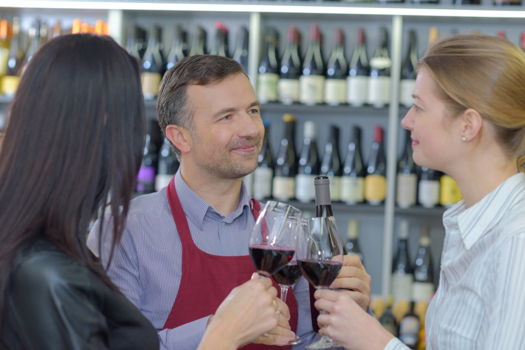 People sampling red wine in a store