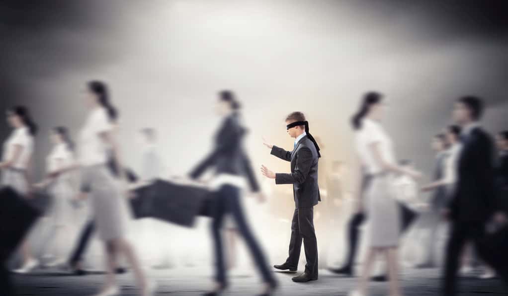 Blindfolded businessman trying to find his way in a crowd