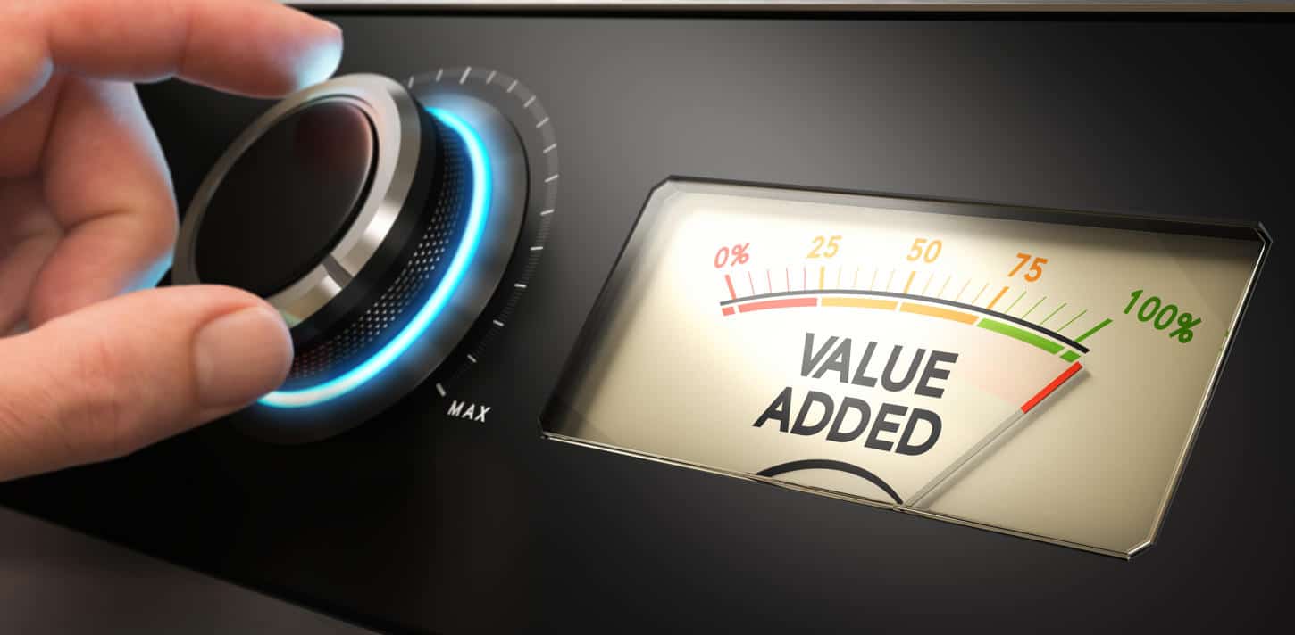 Hand turning a knob up to the maximum with a dial where it is written the text value added. Concept image for illustration of competitive advantage.