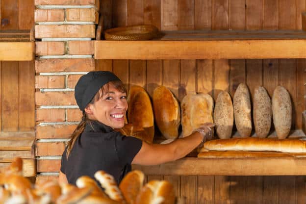 Charming bakery shop with a smiling female baker offers a fresh, artisanal baked goods
